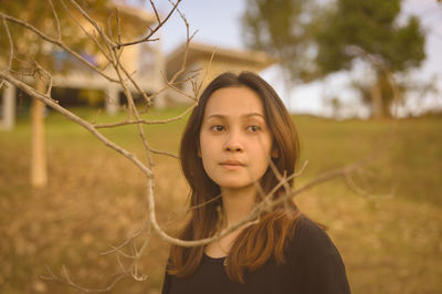 Portrait of young woman standing on field