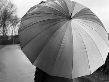 Close-up of person using an umbrella against sky