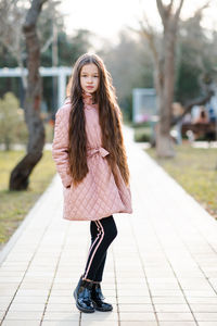 Portrait of young woman standing on footpath