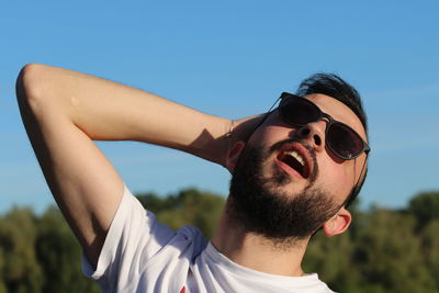 Portrait of young man wearing sunglasses against sky