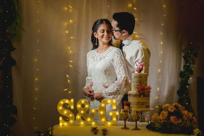 Romantic newlywed couple standing by table in wedding ceremony