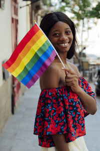 Happy young woman holding rainbow flag