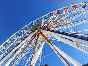 Low angle view of ferris wheel against clear blue sky