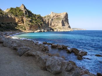 Rock formations in sea against clear blue sky