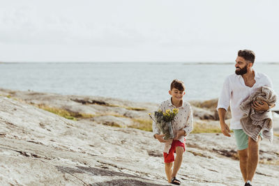 Smiling father holding blanket while bonding with son during summer