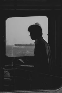 Side view of young man looking through window