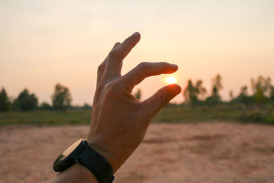 Optical illusion of hand holding sun during sunset
