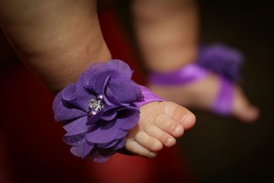 Close-up of baby legs with artificial flowers decoration