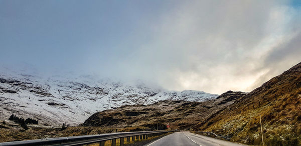 Road by mountains against sky