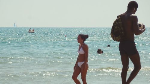 Children playing on beach against clear sky