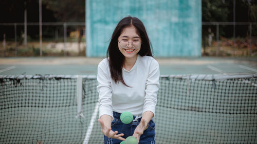 Young woman playing with balls at tennis court