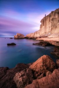 Scenic view of rock formation by sea during sunset