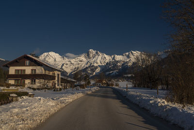 Road amidst snowcapped mountains against clear sky