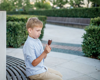 Full length of boy sitting on mobile phone