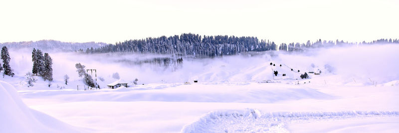 Panoramic view of snow covered land against sky