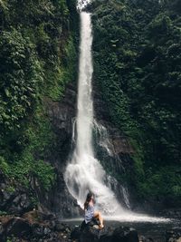 Woman sitting against waterfall