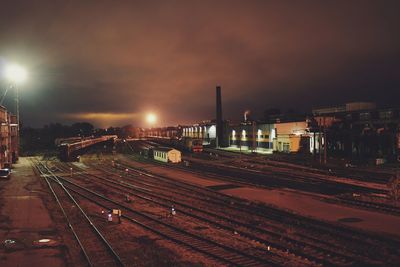 Illuminated railroad tracks against sky at night