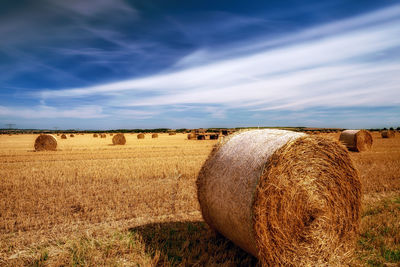 Hay bales on field against sky