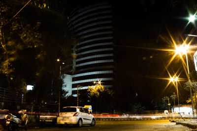 Cars on road by illuminated buildings in city at night