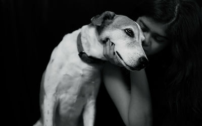 Young woman embracing while sitting with dog in darkroom