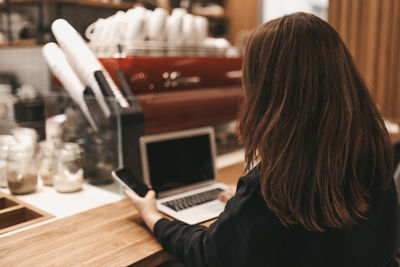Adult confident serious smiling business woman freelancer working in cafe using a laptop and phone