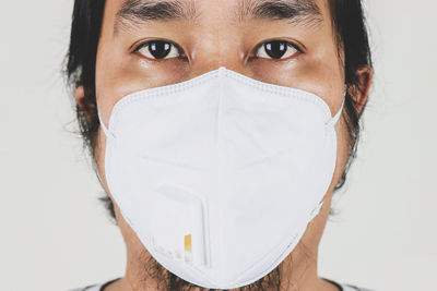 Close-up portrait of man wearing flu mask against white background
