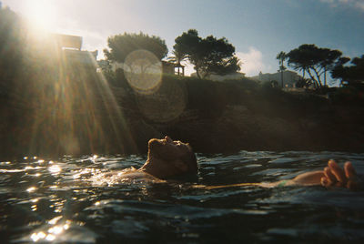 Surface level of person floating in sea against sky