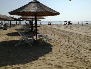 Deck chairs on beach against sky