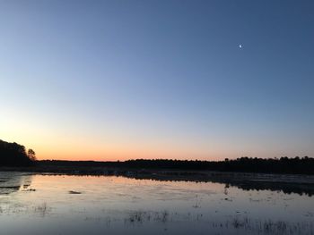 Scenic view of lake against clear sky at sunset