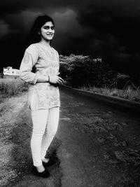 Portrait of smiling young woman standing against sky