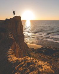 Man photographing at beach during sunset