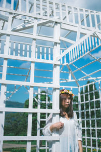 Portrait of young woman standing against building