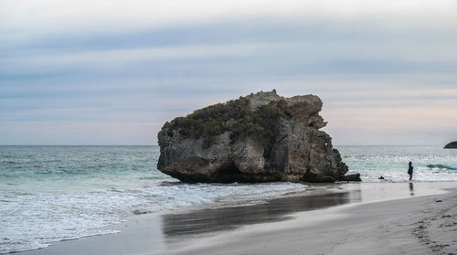 Rock on beach against sky