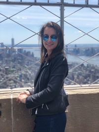 Portrait of smiling young woman standing against railing