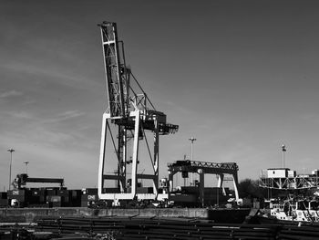 Cranes at harbor against sky