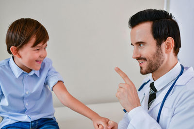 Cheerful doctor and boy gesturing at hospital