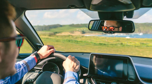 Cropped image of man driving car on field