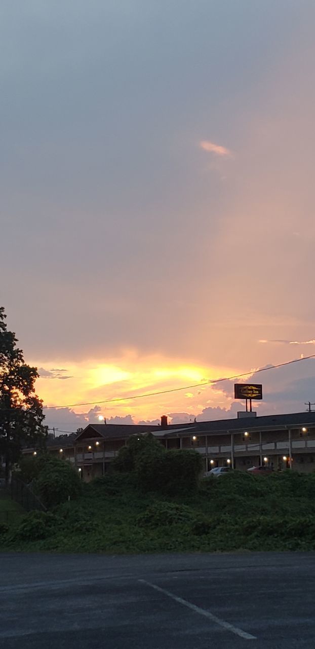 ROAD BY BUILDINGS AGAINST ORANGE SKY