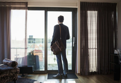 Rear view of businessman looking through window in hotel room