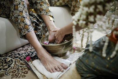Midsection of bride washing woman legs on floor