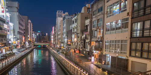 Canal amidst buildings in city at night