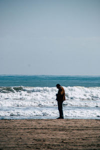 Full length of woman standing on beach against sky