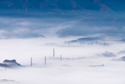 Electricity pylon on foggy weather against sky