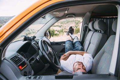 Young man with leg prosthesis resting in camper van