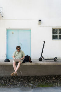 Man with electric scooter using laptop outdoors