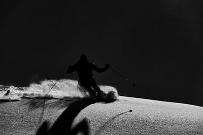 Silhouette man with arms raised standing on snow