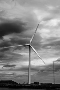 Low angle view of wind turbine against cloudy sky