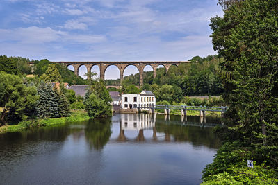 Arch bridge over river against sky