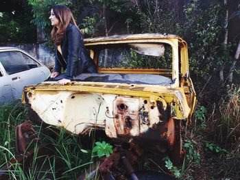 Smiling woman standing in abandoned car