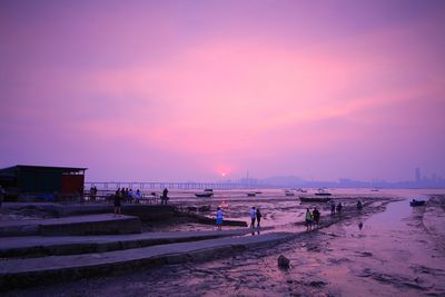 People on beach against sky during sunset